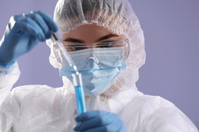 Scientist taking sample of light blue liquid on grey background