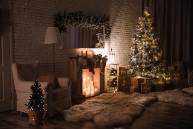 Photo of Stylish interior with beautiful Christmas tree and artificial fireplace at night