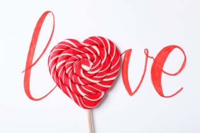 Photo of Word Love with heart shaped lollipop on white background, top view. Valentine's day celebration