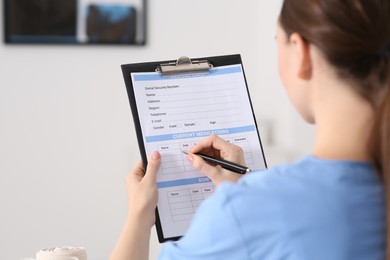 Doctor filling patient's medical card in clinic, closeup