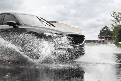 Modern car driving outdoors on rainy day