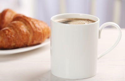 Cup of tasty aromatic coffee and croissants for breakfast on white table