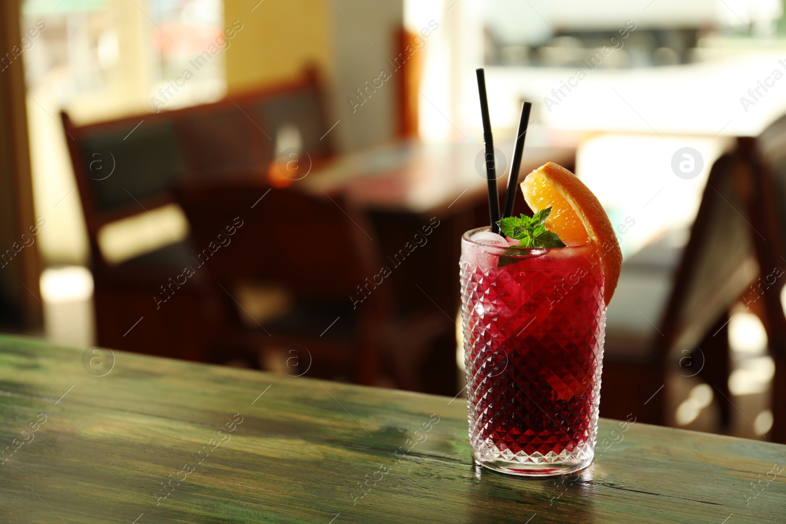 Photo of Glass of delicious cocktail with ice on table in bar