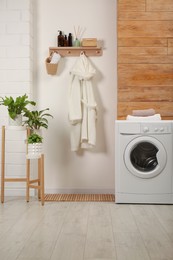 Wooden shelf with toiletries and robe on beige wall in bathroom. Interior design