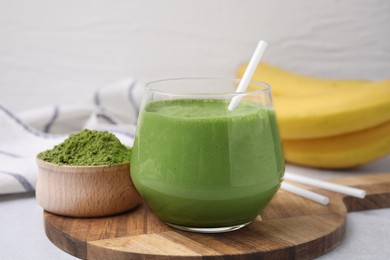 Glass of tasty matcha smoothie and powder on light table