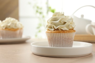 Photo of Tasty cupcake with vanilla cream on light wooden table, closeup. Space for text