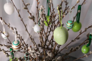 Photo of Beautiful willow branches with painted eggs indoors. closeup. Easter decor