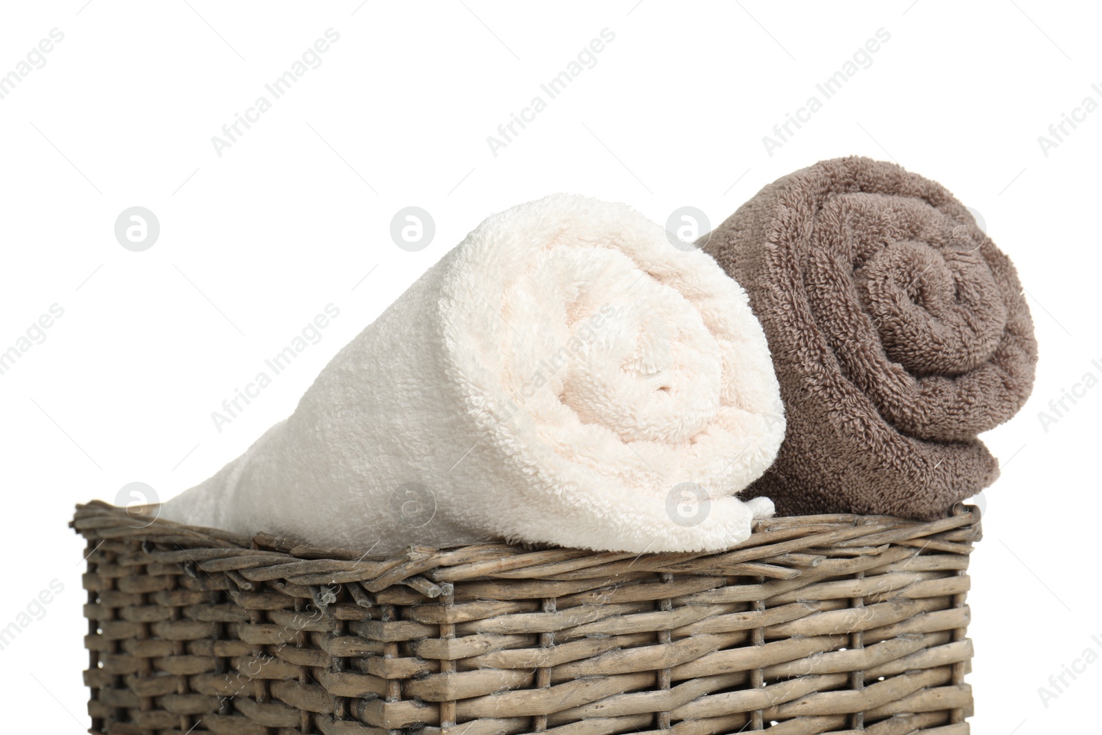 Photo of Rolled soft terry towels in wicker basket on white background