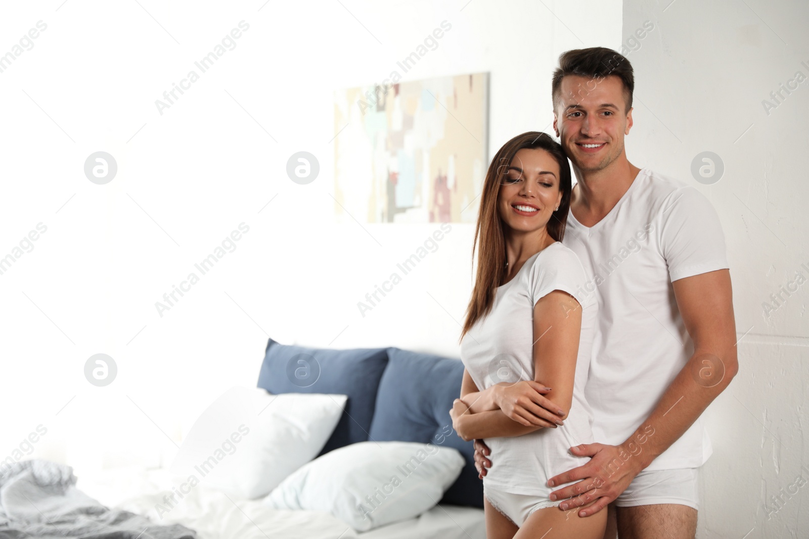 Photo of Happy couple wearing underwear in modern bedroom