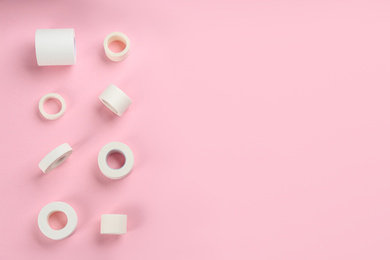Sticking plaster rolls on pink background, flat lay. Space for text