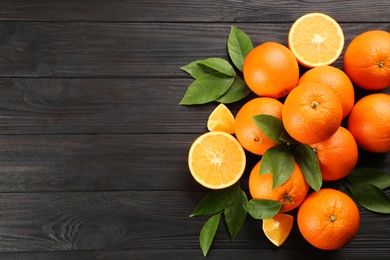 Photo of Delicious ripe oranges on black wooden table, flat lay. Space for text