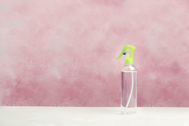 Spray air freshener on table against color background