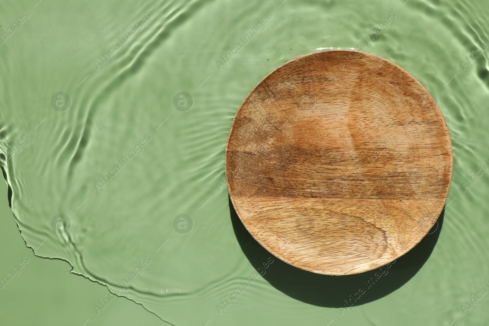 Photo of Presentation of product. Wooden podium in water on green background, top view. Space for text