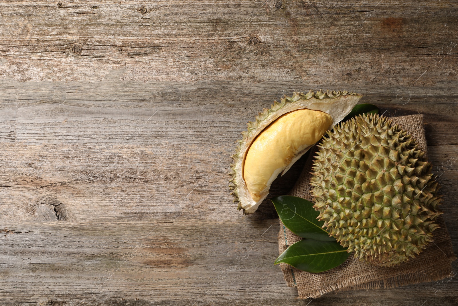 Photo of Fresh ripe durian fruits on wooden table, flat lay. Space for text