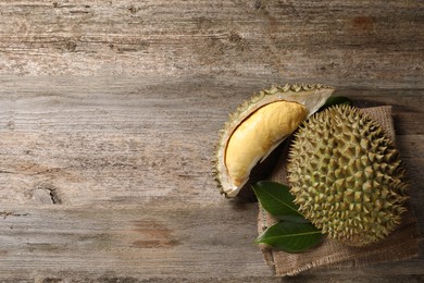 Fresh ripe durian fruits on wooden table, flat lay. Space for text