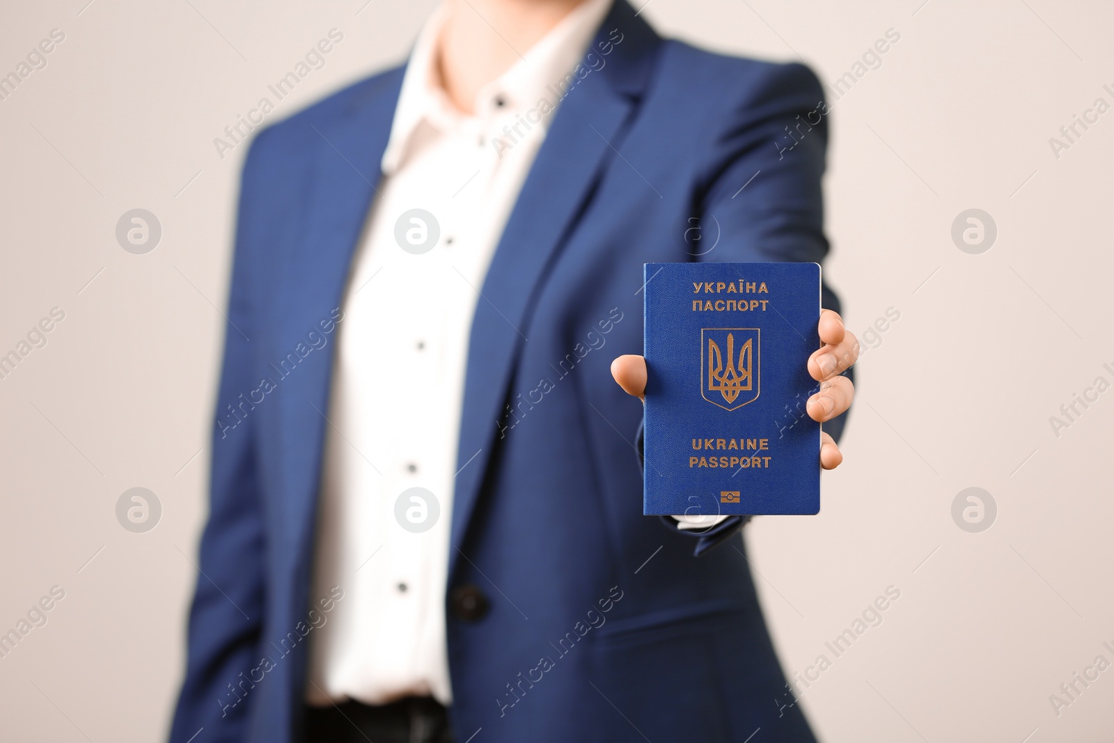 Photo of Woman holding Ukrainian travel passport on light background, closeup. International relationships