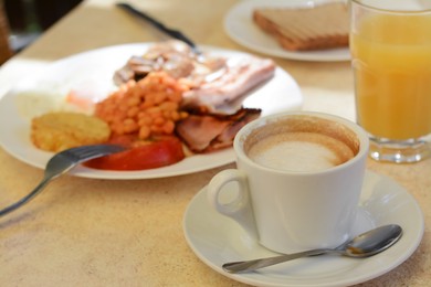 Photo of Cup of coffee and delicious breakfast served on beige table