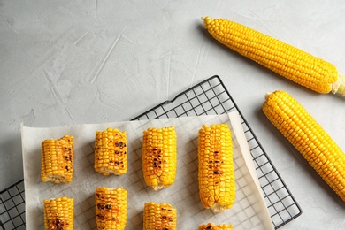 Cooling rack with grilled corn cobs on light background, top view