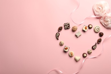 Photo of Heart made with delicious chocolate candies on light pink background, flat lay. Space for text