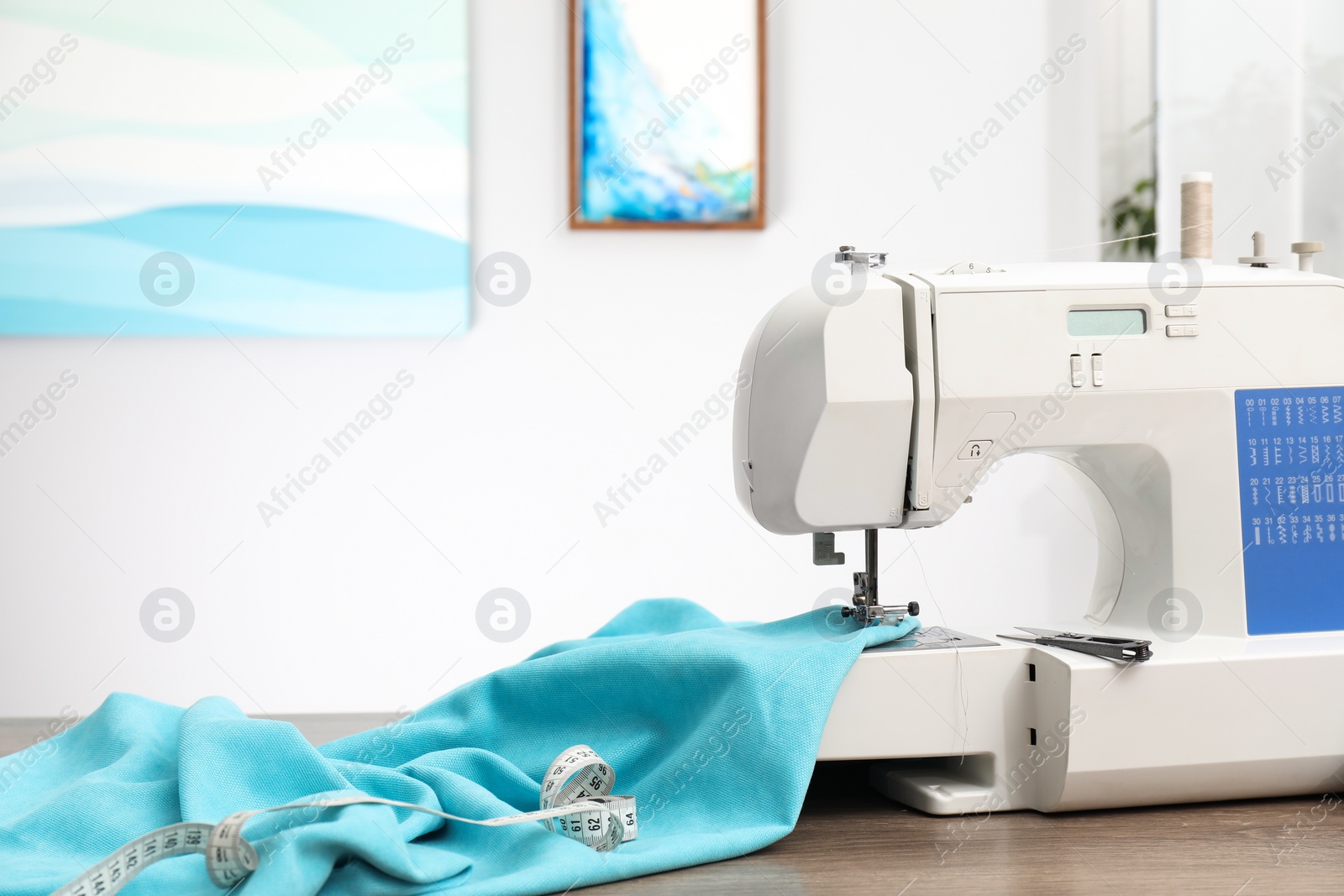 Photo of White sewing machine and cloth on wooden table indoors