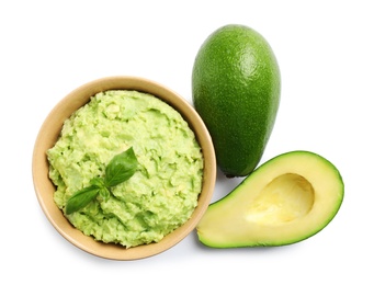 Photo of Bowl of tasty guacamole with basil and avocados on white background, top view