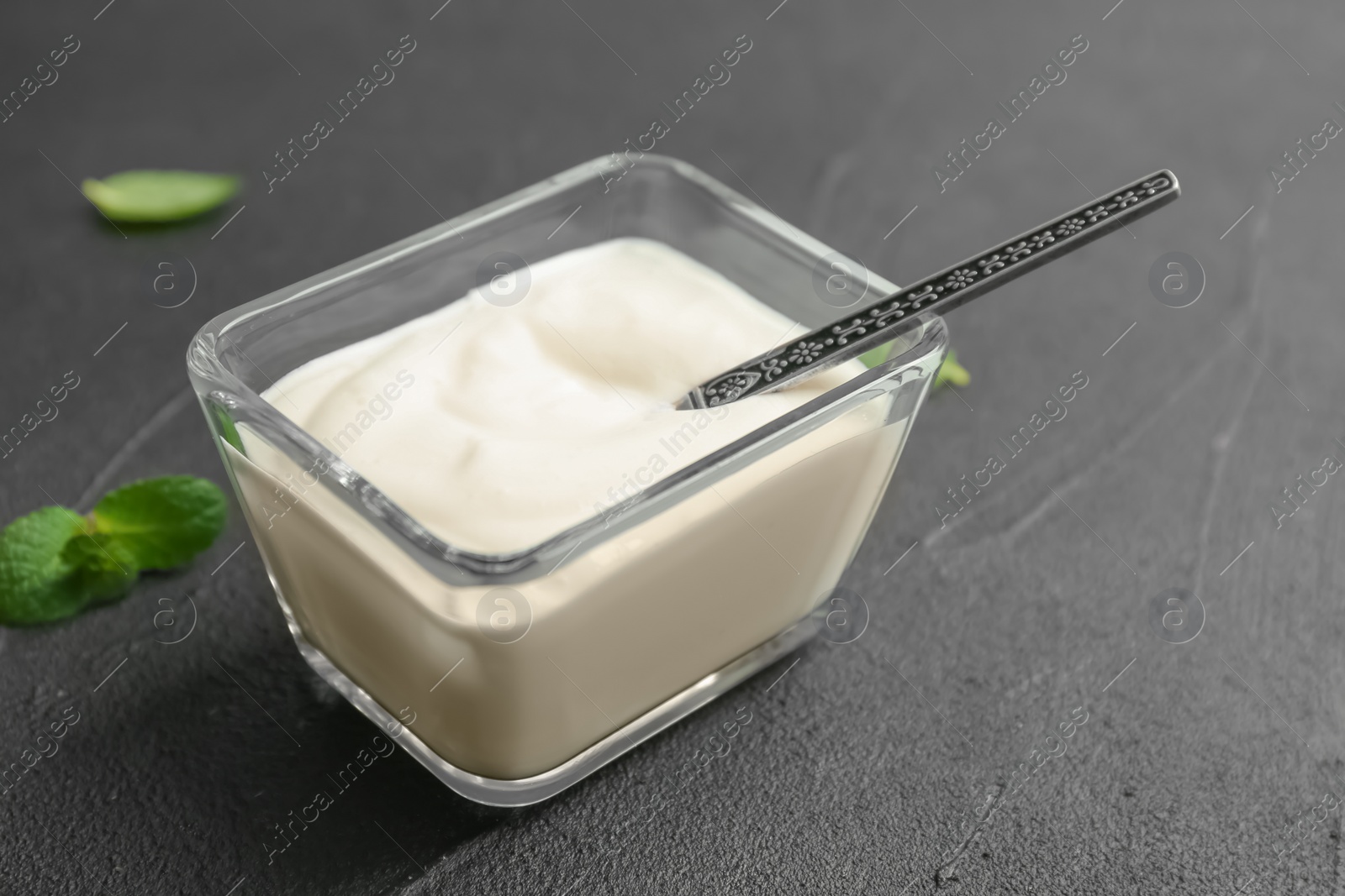 Photo of Glass bowl with yummy yogurt on grey background