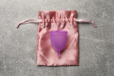 Menstrual cup and cotton bag on grey background, top view. Reusable feminine hygiene product