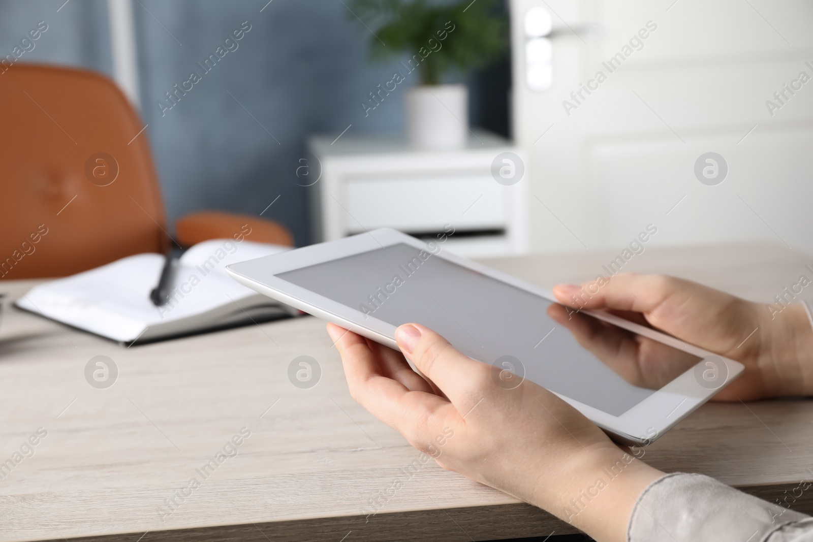 Photo of Woman using modern tablet at workplace indoors, closeup