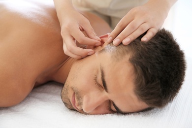 Young man undergoing acupuncture treatment in salon, closeup