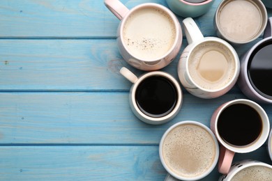 Many cups of different coffee drinks on light blue wooden table, flat lay. Space for text