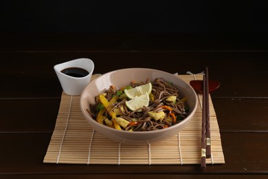 Photo of Stir-fry. Delicious cooked noodles with chicken and vegetables in bowl served on wooden table