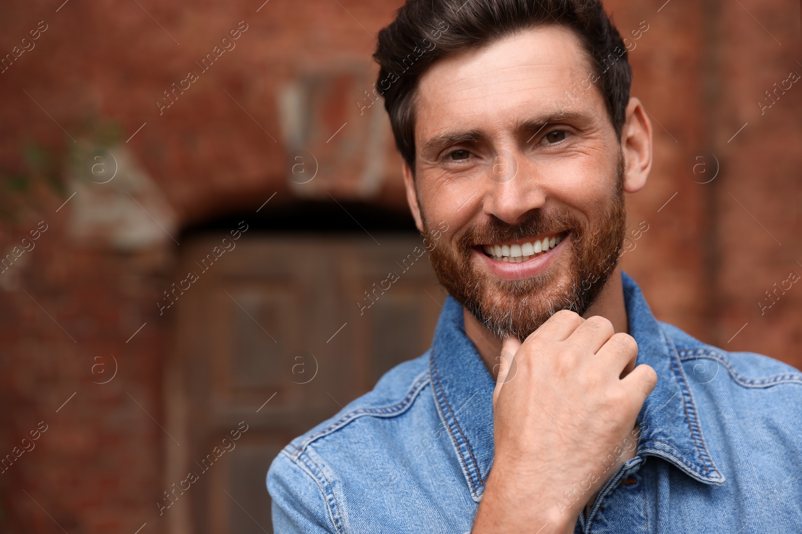 Photo of Smiling handsome bearded man outdoors. Space for text