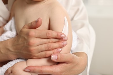 Mother applying body cream onto baby`s skin, closeup