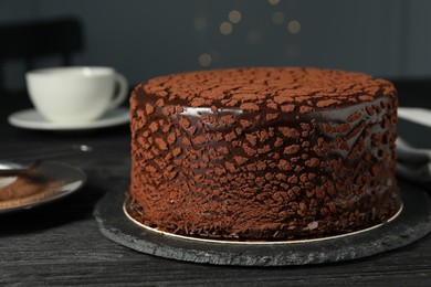 Delicious chocolate truffle cake on black wooden table