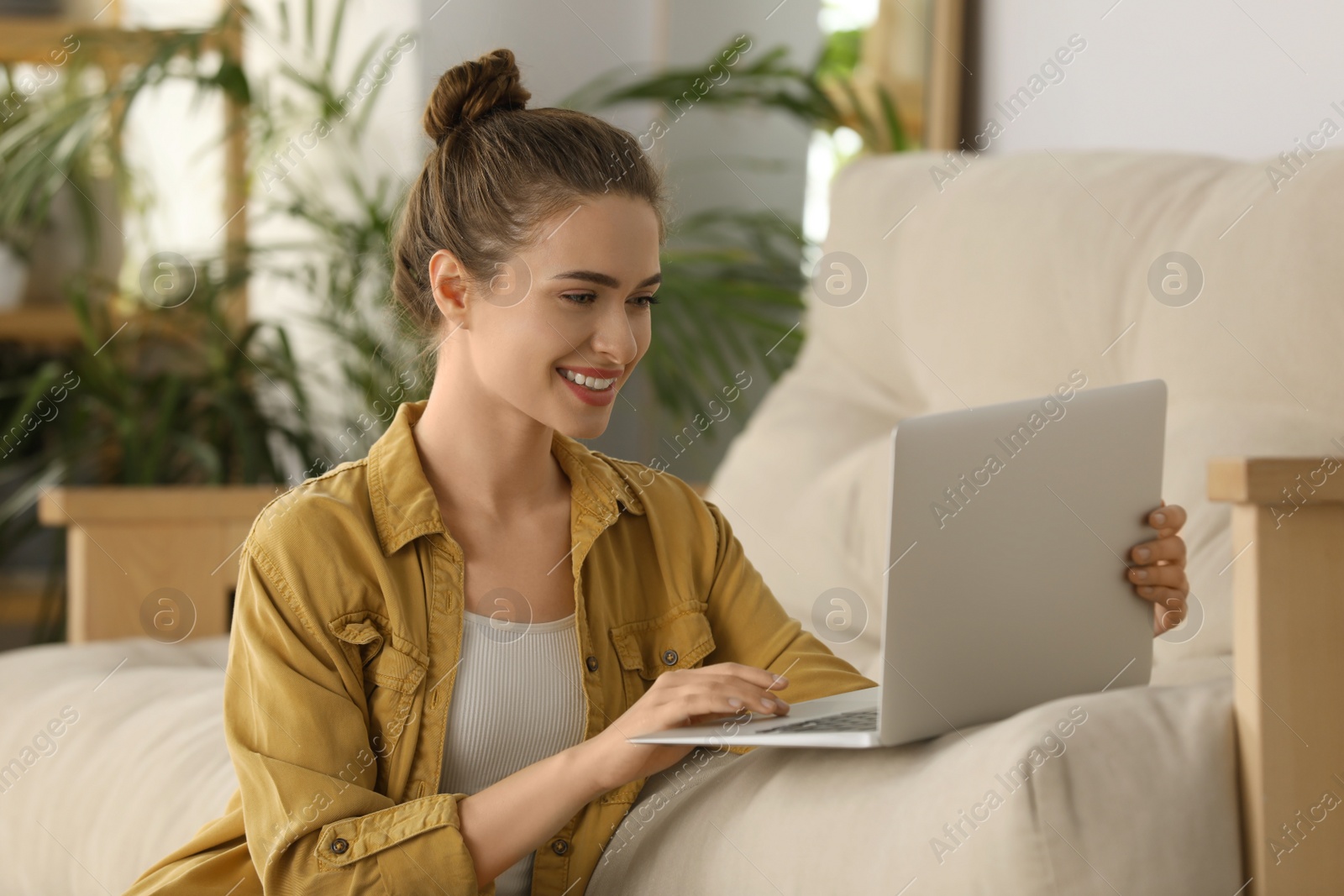 Photo of Happy young woman with laptop in living room