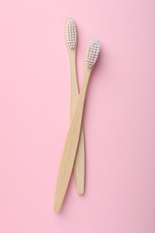 Photo of Bamboo toothbrushes on pink background, flat lay