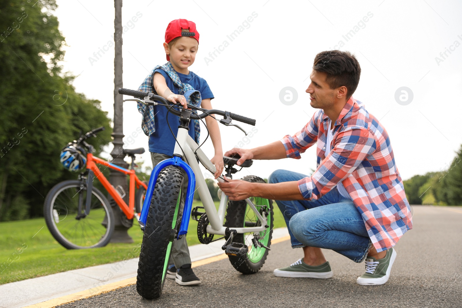 Photo of Dad teaching son to ride bicycle outdoors