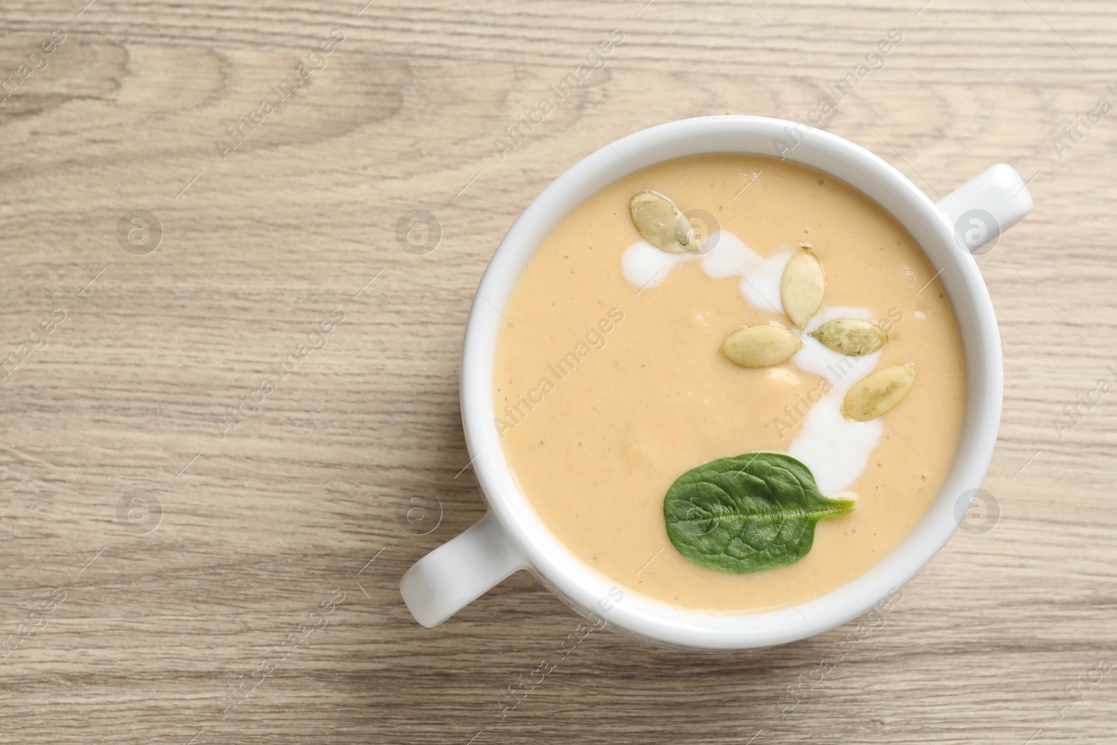 Photo of Healthy cream soup high in vegetable fats on wooden table, top view. Space for text