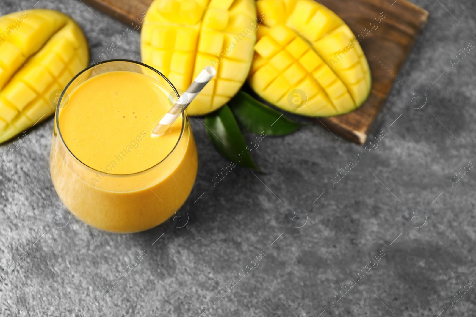 Photo of Fresh delicious mango drink on grey table. Space for text