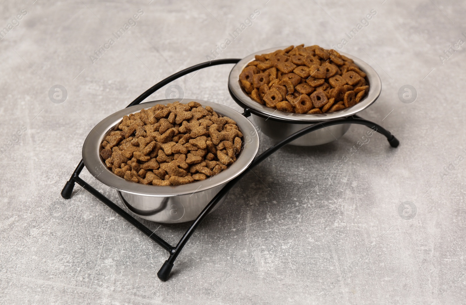 Photo of Dry food in pet bowls on grey surface