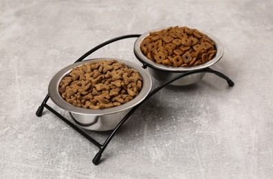 Photo of Dry food in pet bowls on grey surface