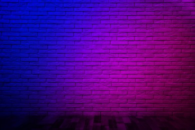 Room with brick wall and wooden floor in neon lights