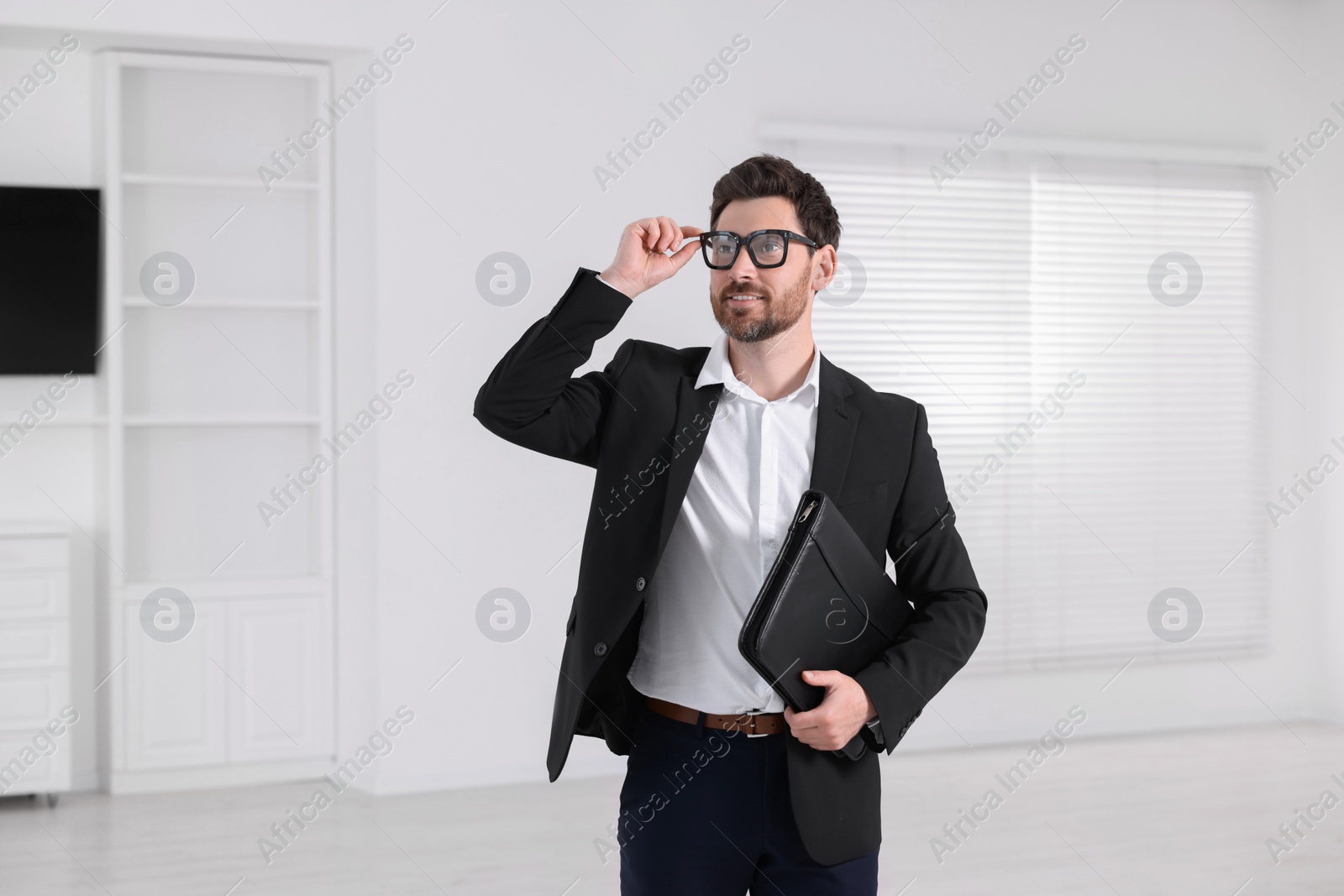 Photo of Happy real estate agent with leather portfolio in new apartment