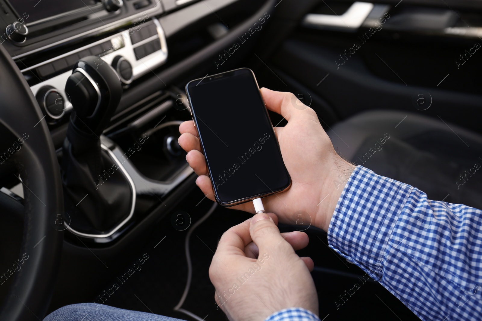 Photo of Man charging phone with USB cable in car