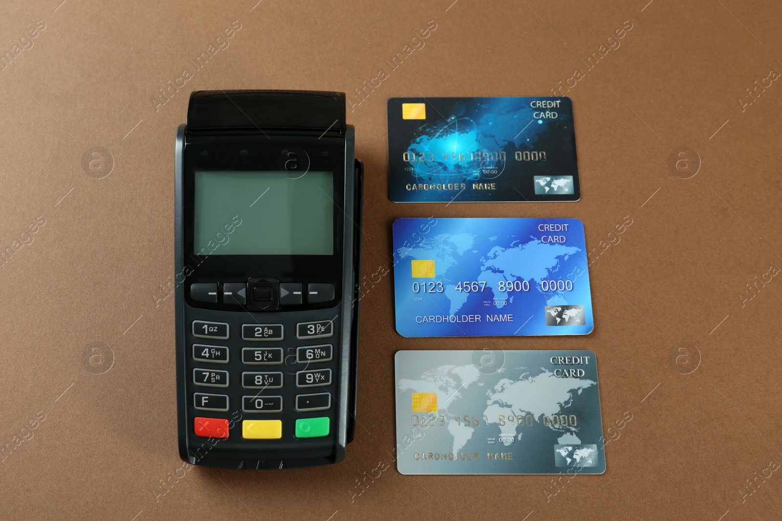 Photo of New modern payment terminal and credit cards on brown background, above view