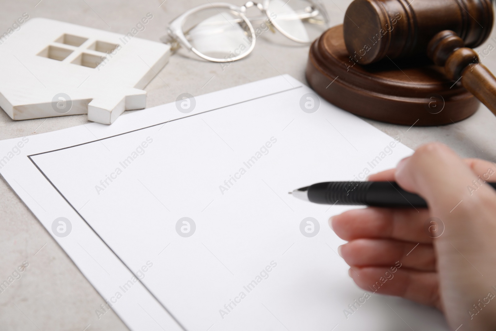 Photo of Woman signing last will and testament at light grey table, closeup