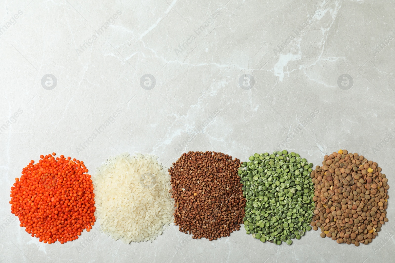 Photo of Flat lay composition with different types of legumes and cereals on grey marble table, space for text. Organic grains