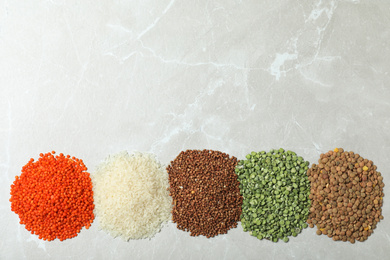 Photo of Flat lay composition with different types of legumes and cereals on grey marble table, space for text. Organic grains