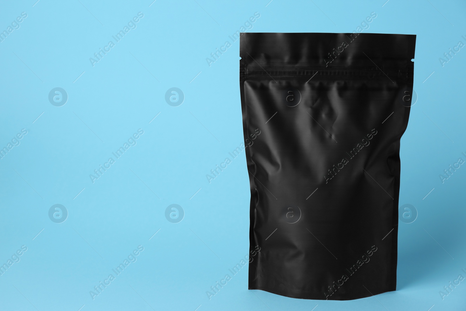 Photo of One blank foil package on light blue background. Space for text