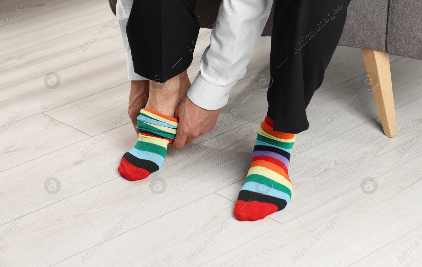 Photo of Man putting on colorful socks indoors, closeup